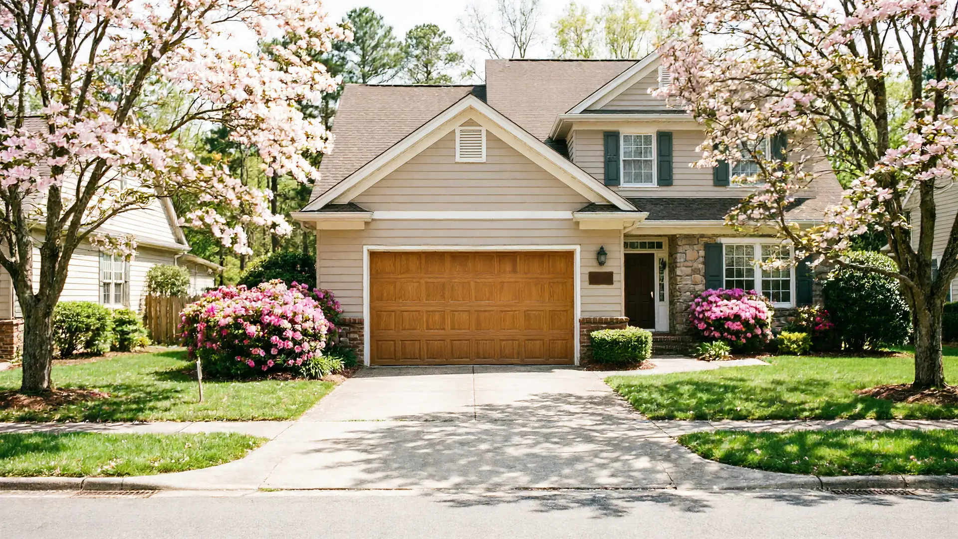 The house has a brown garage door, light siding, and green shutters.